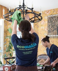 Two maids performing house cleaning services on a dinning room table and chandelier in Rancho Cucamonga.