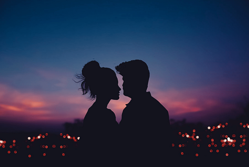 A couple near a view of a skyline during nighttime