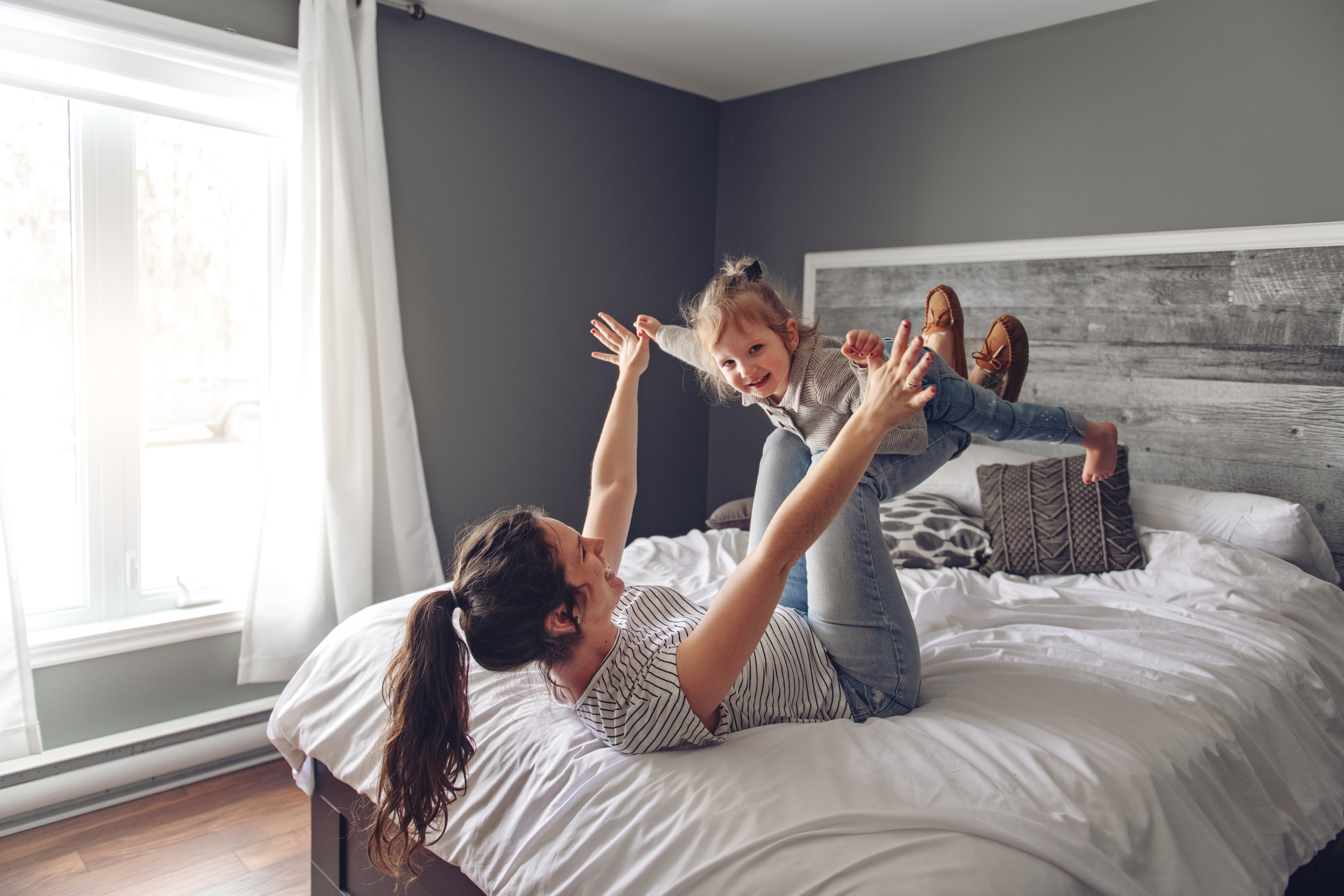 A mom and a girl playing on a bed after receiving ecomaids deep cleaning services in Sugar Land.